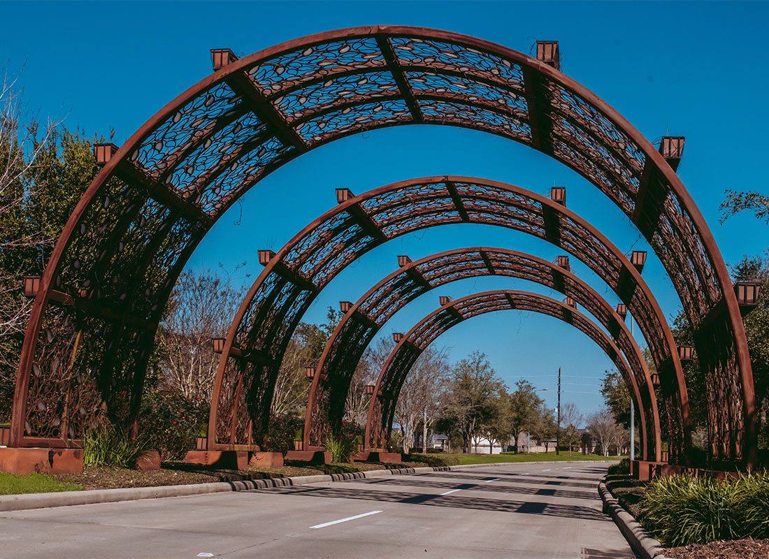 Katy, TX - Large Bonze Archway Over a Road in a Residential Community in Katy Texas Against a Bright Blue Sky