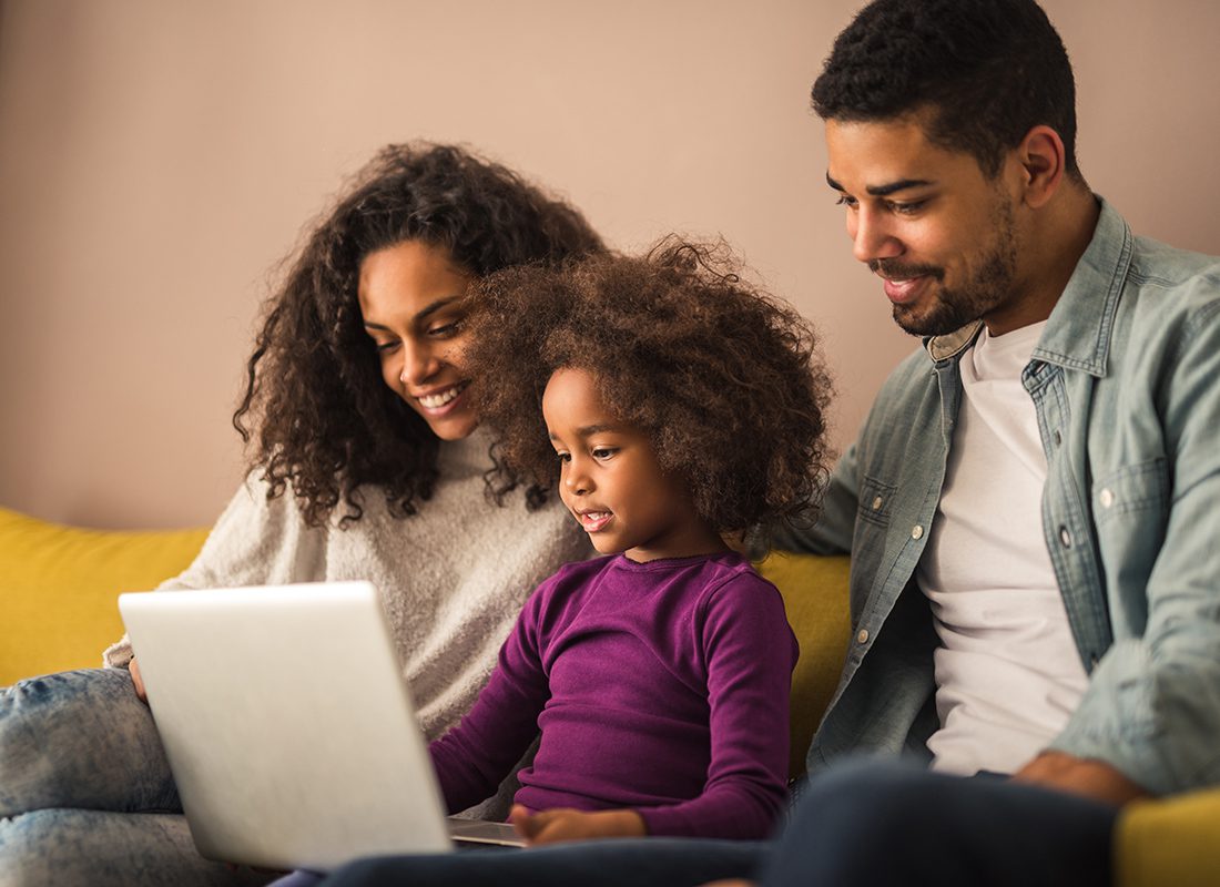 Life Insurance Simplified - Family Sitting on Couch Looking at Computer in Their Home